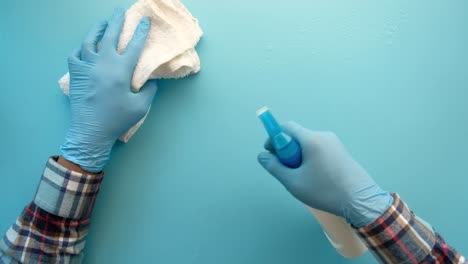 cleaning a blue wall with gloves and a cloth