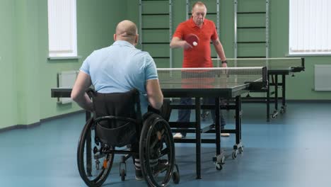 a man in a wheelchair plays ping pong. people with disabilities play table tennis. rehabilitation of the disabled. paralympic sport.