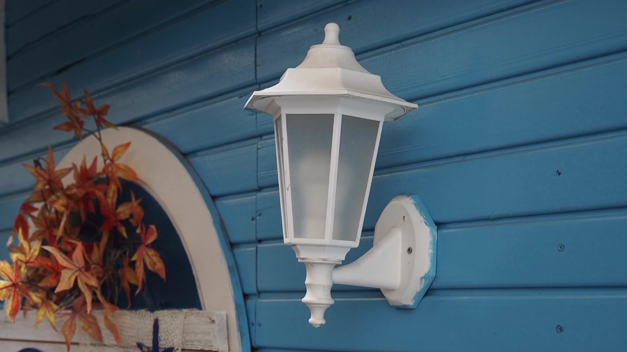Lampu Dinding Putih di Dinding Kayu Biru dengan Dekorasi Musim Gugur