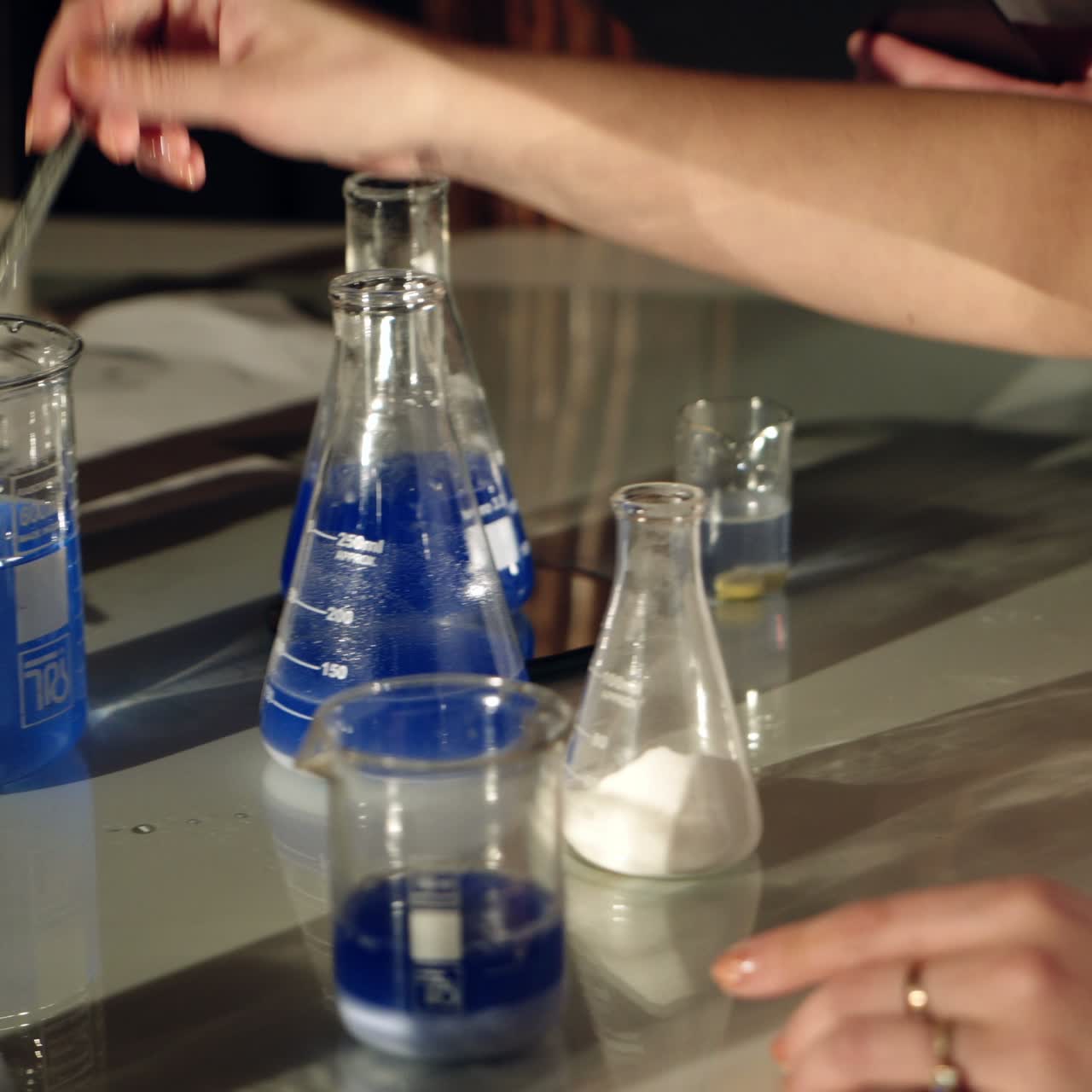Scientists examining liquids in beakers. Experiments in a chemistry lab. Close-up