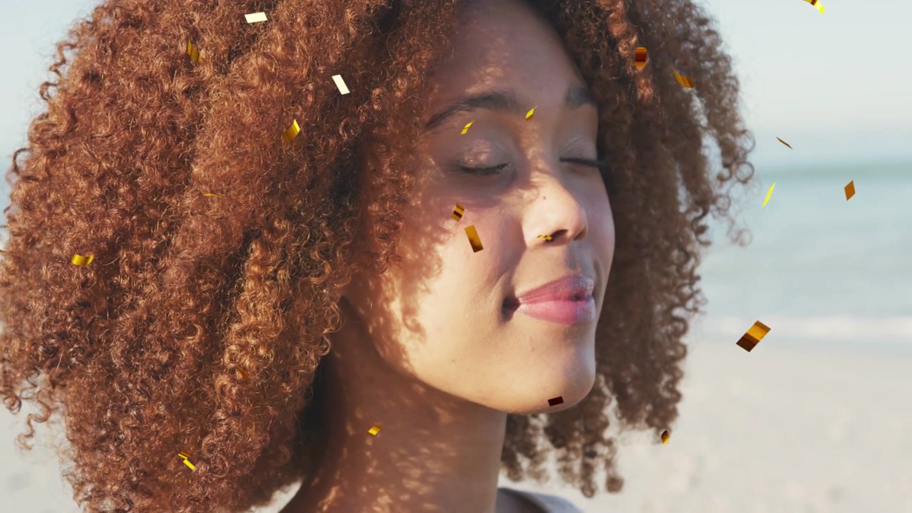 Donna in piedi sulla spiaggia, con coriandoli che iniziano a fluttuare sul viso, che chiude gli occhi per scopi di marketing
