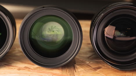 various camera lenses with reflections lined on wooden table