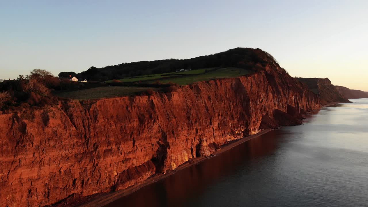 toma aérea de los acantilados de la costa jurásica en sidmouth, suroeste de inglaterra, iluminado en rojo desde un hermoso amanecer