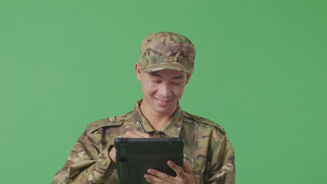 close up of asian man soldier taking note on a tablet while standing in the green screen background studio
