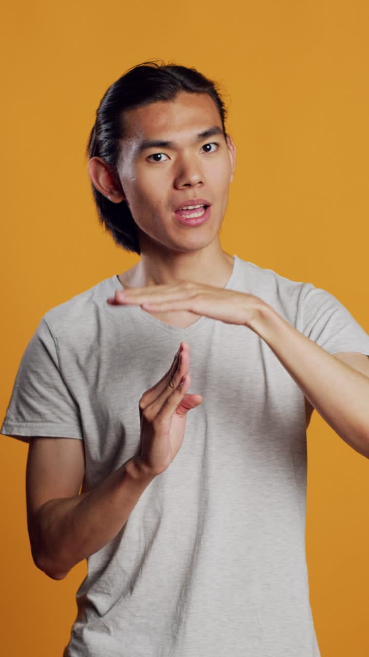 Vertical video: Young adult doing t shape symbol on camera