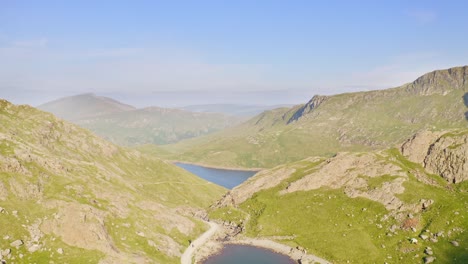 Increíble-Grúa-Aérea-Revelada-Sobre-El-Parque-Nacional-De-Snowdonia-En-Gales-Con-Cadenas-Montañosas-Y-Lagos-Debajo-En-Una-Mañana-Clara