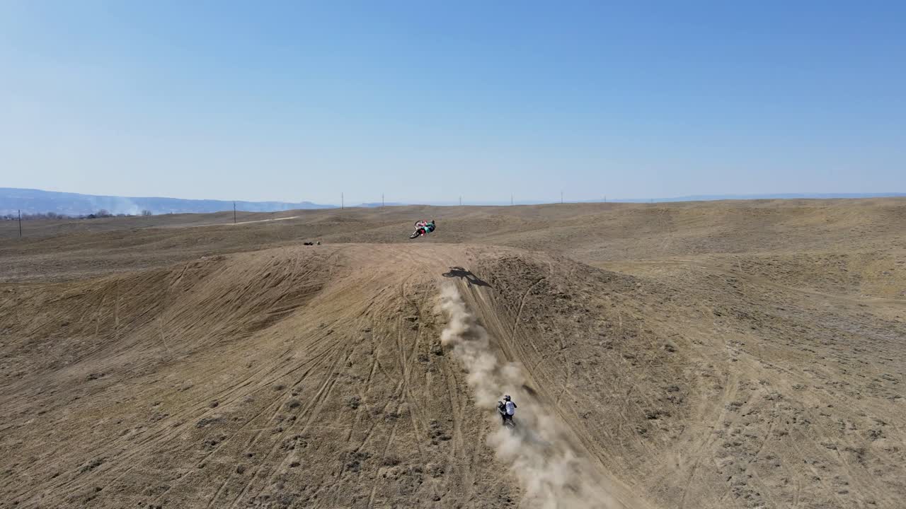 un drone de 4k lleno de acción de dos corredores de motocross golpeando un gran salto de colina, en el terreno desértico del área de grand valley ohv, ubicado en grand junction, colorado