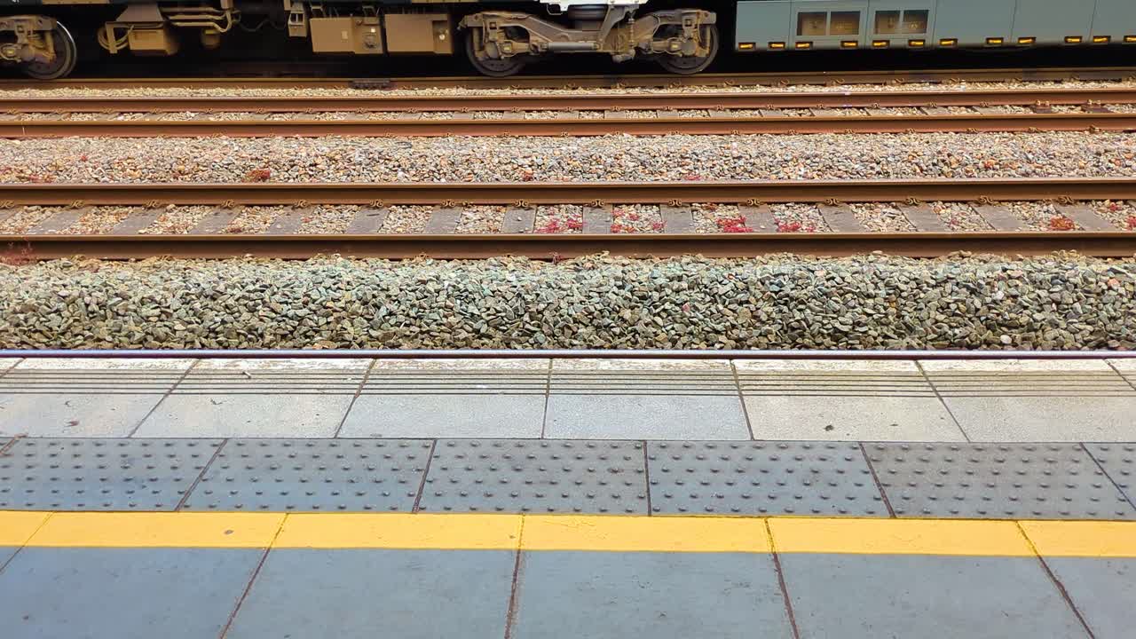 Static View from Platform Station as Train Departs on Opposite Side. Public Transportation Footage on British Rail Network. Wooden Sleepers Supporting Hot Rolled Steel for Carriage to Ride On