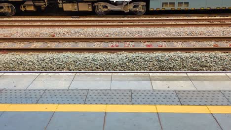 static view from platform station as train departs on opposite side. public transportation footage on british rail network. wooden sleepers supporting hot rolled steel for carriage to ride on