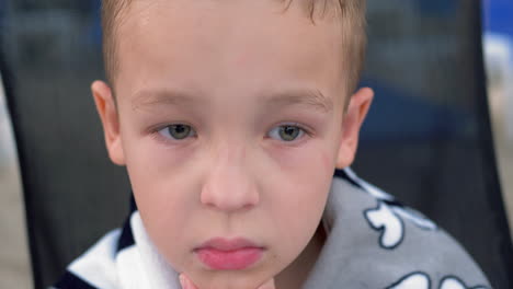 thoughtful boy wrapped in towel after bathing in sea