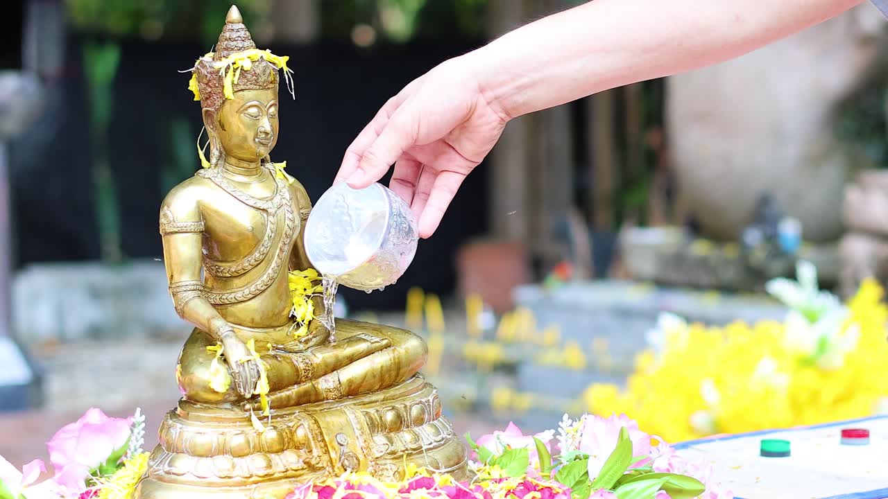 Sequential water offering to a golden Buddha statue