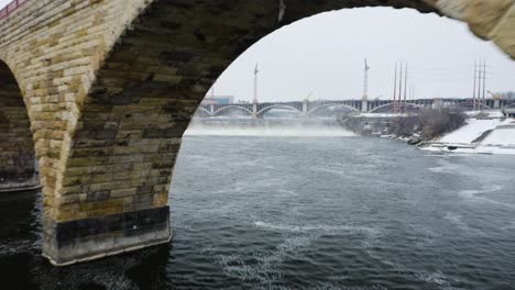 Drone-Flies-Between-Stone-Arch-Bridge,-Over-Saint-Anthony-Falls