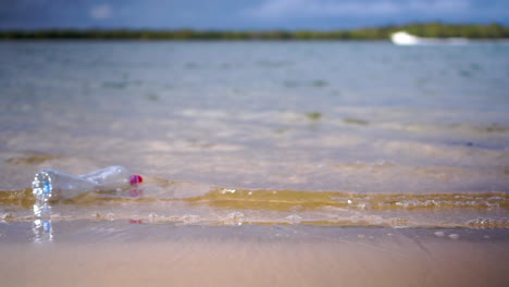 Plastikflasche-Wird-Von-Kleinen-Wellen-Vom-Strand-Gespült-Und-Schwimmt-Dann-Davon