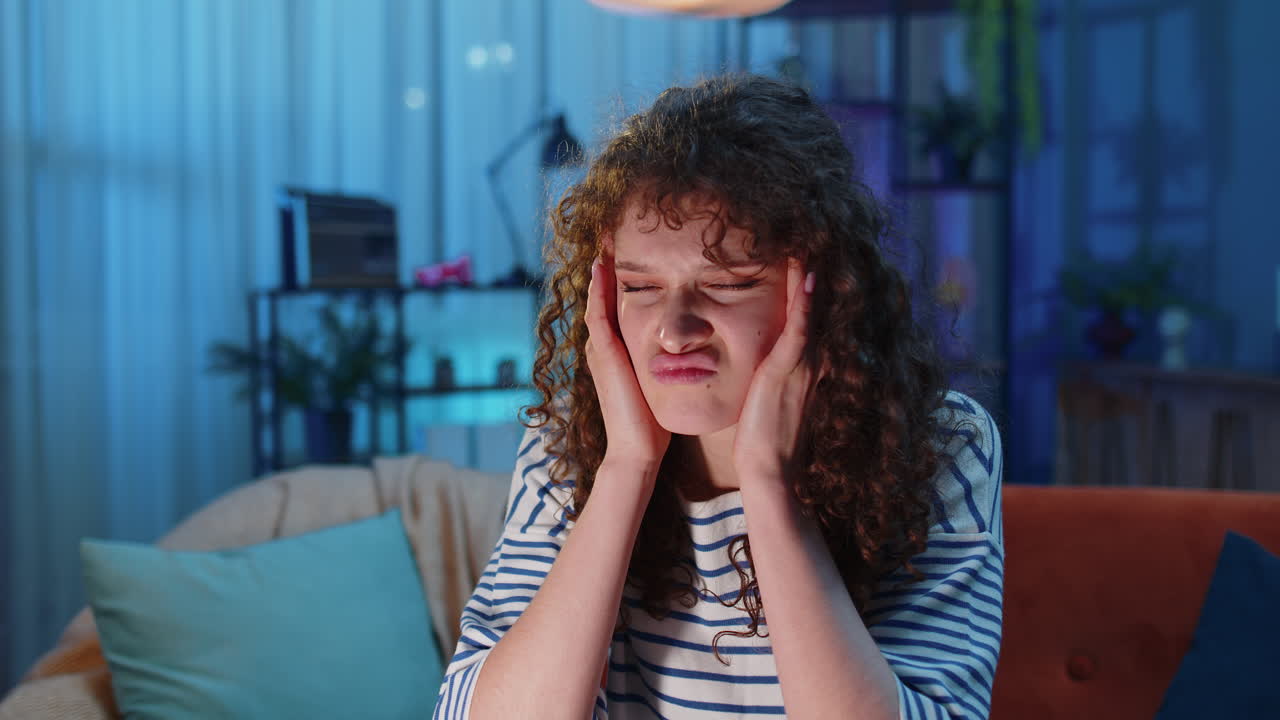 Displeased woman rubbing temples to cure headache problem, suffering from migraine, stress at home