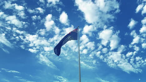 Australische-Flagge-Weht-Im-Wind-Mit-Blauem-Himmel-Und-Flauschigen-Wolken-Im-Hintergrund