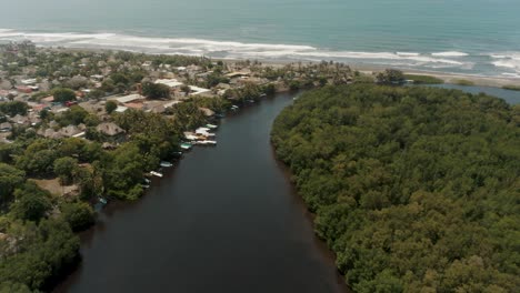 scenery of river surrounded by lush tropical vegetation and seascape in el paredon, guatemala - aerial drone shot