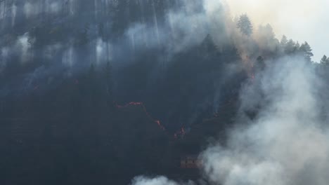 A-wildfire-burning-a-steep-hillside-in-Nepal-in-the-dry-season-with-smoke-reaching-into-the-sky