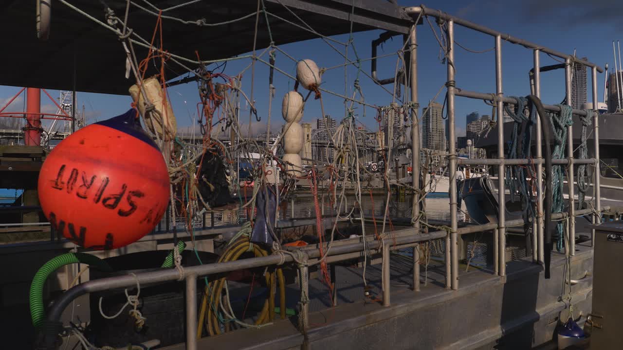Fishing Boat with fisherman's Nets and Buoys Left to Dry by Boat Dock of the city marina bay cityscape in the background bridge blue sky