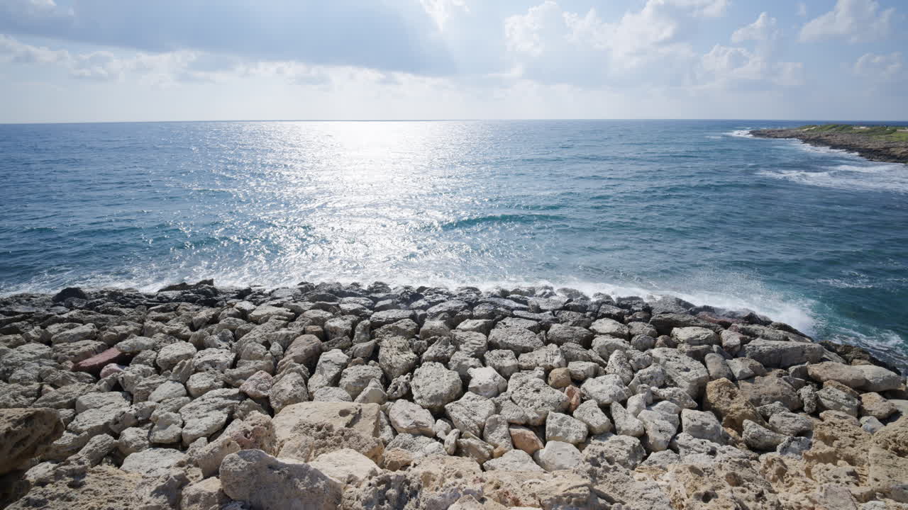 Primo piano di rocce calcaree aspre lungo la costa con il Mar Mediterraneo sullo sfondo.