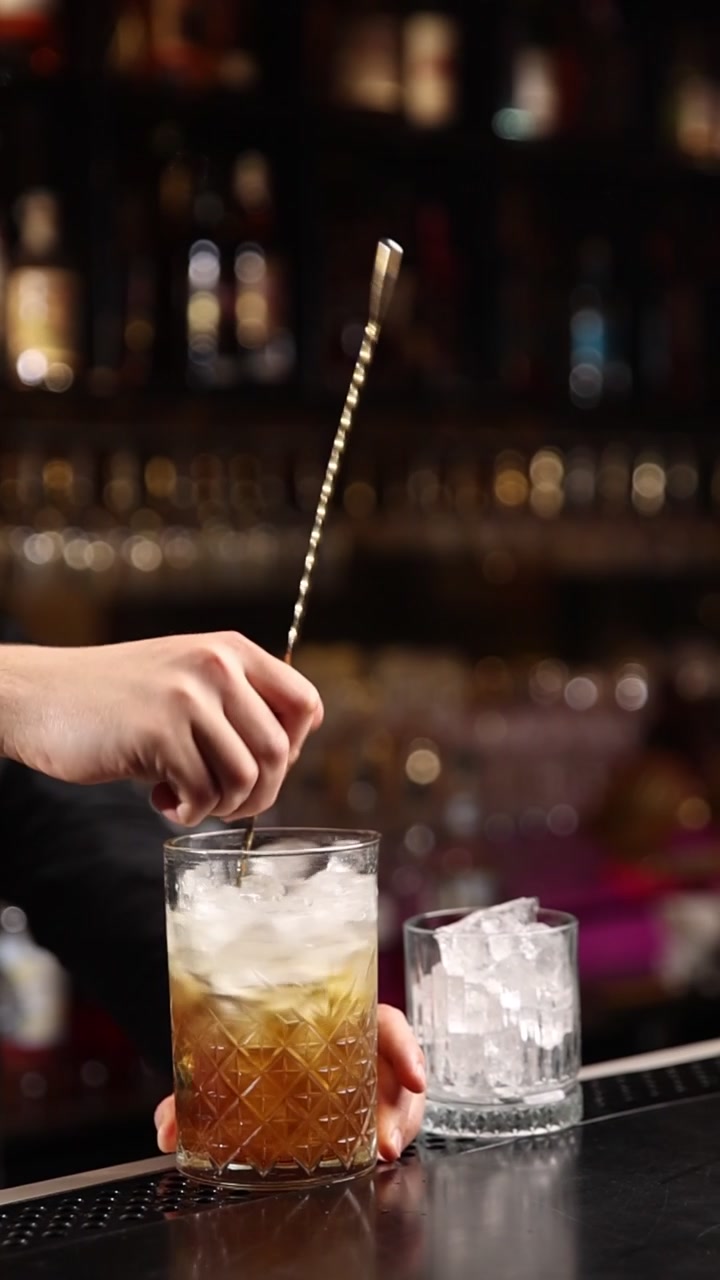 Barman che mescola un cocktail con ghiaccio in un bicchiere
