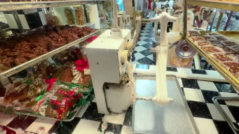 Up-close-static-view-of-salt-water-toffee-machine-in-candy-store-with-chocolate-near-by