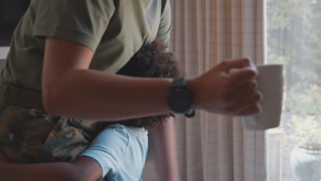 Close-Up-Of-Son-Hugging-Legs-Of-Army-Mother-In-Uniform-Home-On-Leave-In-Family-Kitchen
