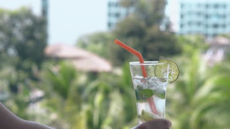 girl holds soft drink against palms waving in light wind