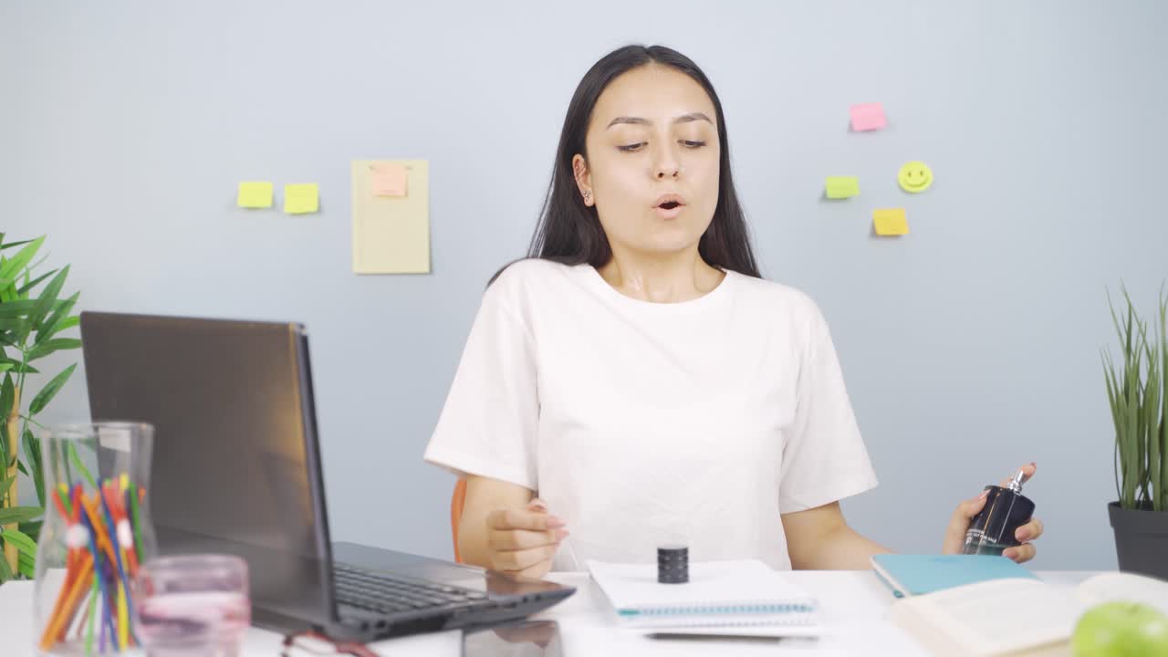 여성 학생이 향수를 스프레이하고 있습니다.