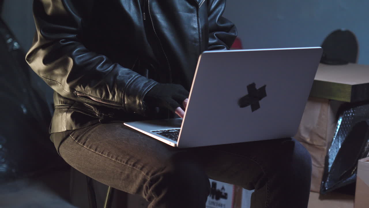 criminal usando máscara de bandido escribiendo en una computadora portátil, luego la cierra y la guarda