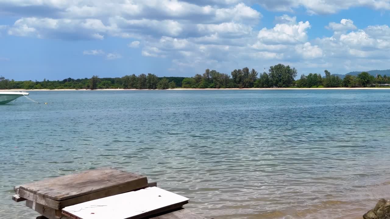 푸켓의 평온한 해변, 은 하늘, 조용한 물, 울창한 초록색의 공중 영상.