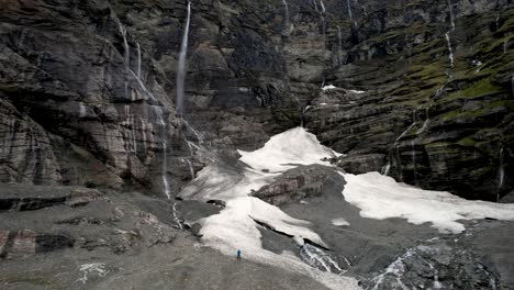 Man-watching-hundred-waterfalls-at-breathtaking-natural-location,-Earnslaw-Burn,-New-Zealand-aerial-panoramic