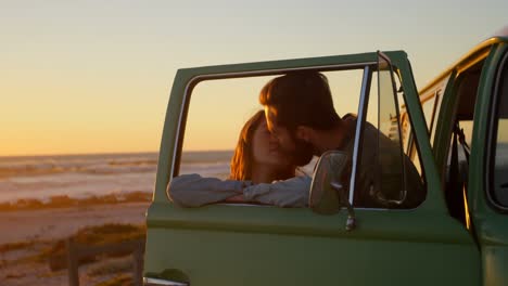 um casal romântico a beijar-se perto de uma carrinha.