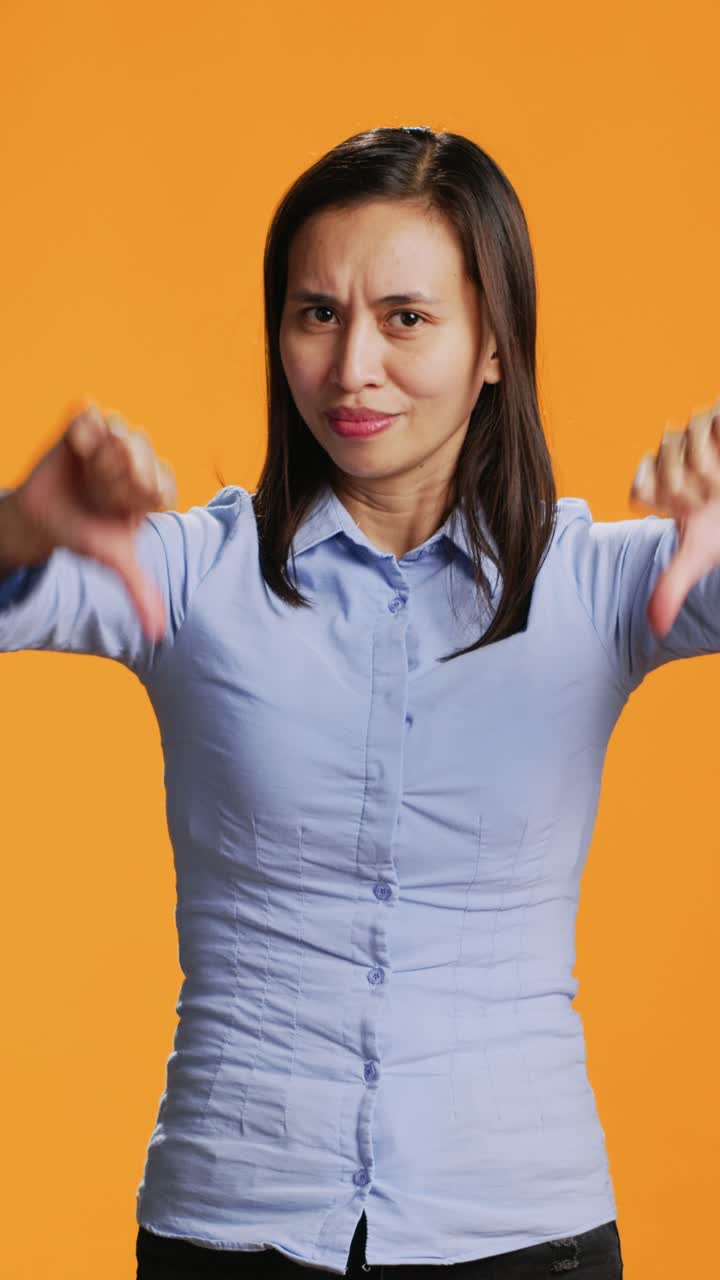 Vertical Video Asian model showing dislike symbol in studio
