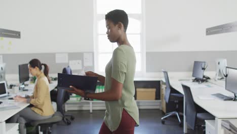 African-american-businesswoman-walking-in-office-and-looking-on-documents