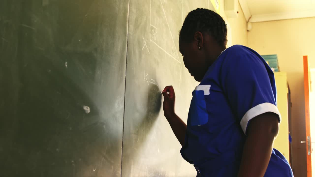 Young schoolgirl writing on the blackboard in class 4k