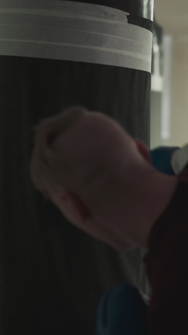 Sportsman fights punching bag training in sports center. Strong athlete with bald head beats hanging item in gym slow motion. Skilled combat master