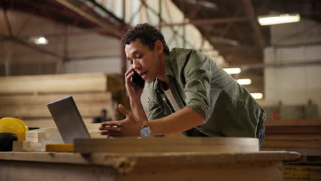 man on phone call working on laptop in warehouse