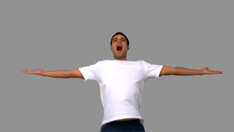 hombre guapo saltando y levantando los brazos en la pantalla gris