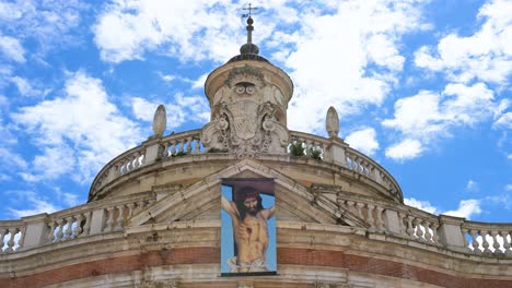 banner of jesus christ on the royal church of san antonio in aranjuez, spain. a symbol of faith on a fine example of 18th-century spanish baroque architecture under a vast, partly cloudy sky.