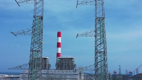 aerial drone footage of high-voltage power towers with prefabricated glass insulators to distribute electricity in an industrial park - development and industrialization concept
