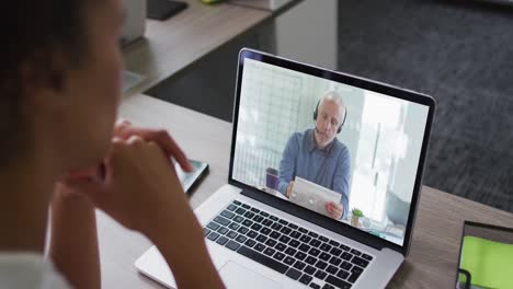 Mid-section-of-african-american-woman-having-a-video-call-with-male-colleague-on-laptop-at-office