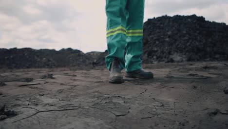 Amidst-the-barren-landscape,-an-industry-worker-stands-on-fractured-mine-soil,-a-stark-reminder-of-the-environmental-costs-and-challenges-tied-to-resource-extraction-and-industrial-progress