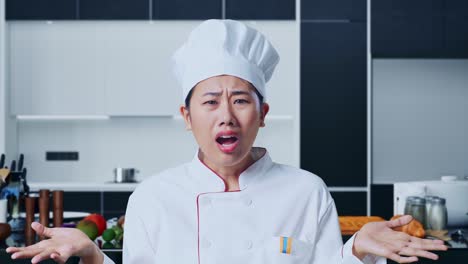 "아시안 여성 요리사가 ""왜?""라고 궁금해하고 집 주방에서 의심스럽게 서 있습니다."
