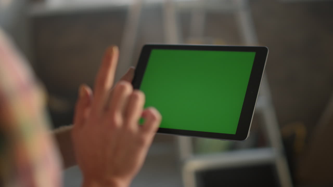 mujer con la mano tocando la pantalla verde. chica desconocida trabajando en una tableta en el interior.