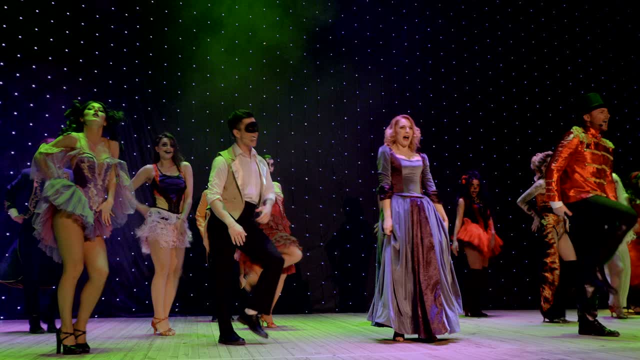 группа сказочных героев танцует и поет на сцене театра.