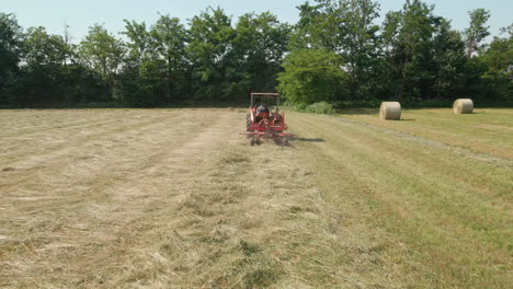 farmer works on tractor making hay for harvesting during summer in italy