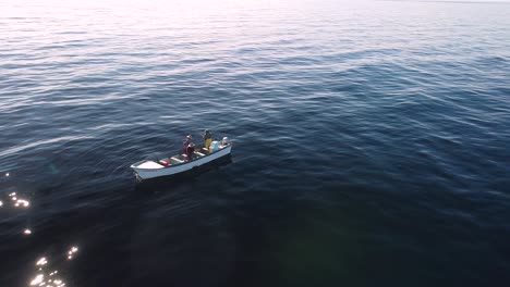 Light-glistens-on-water-as-anglers-reel-in-fish,-open-ocean