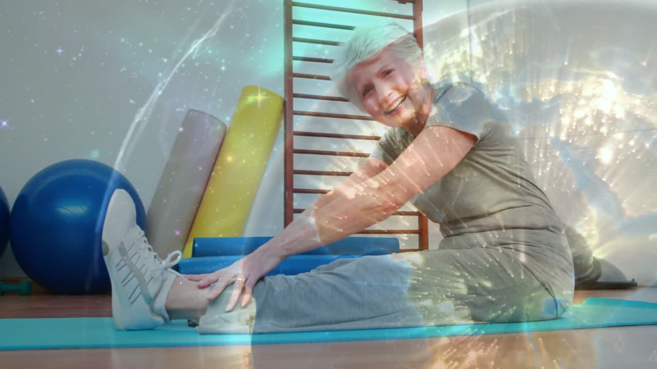 Üstünde overlay bulunan bir mat üzerinde hamstring esnetmesi yapan, ayak bileklerine kadar uzanan yaşlı bir adam
