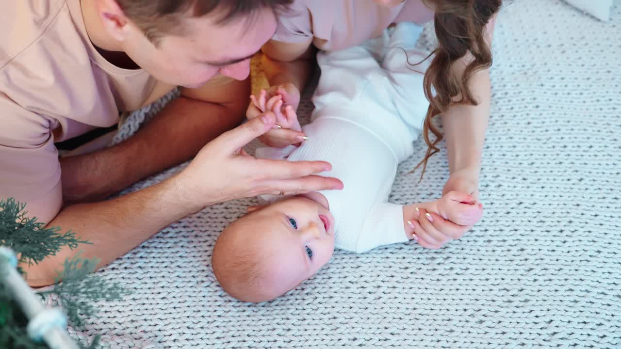 Padres felices jugando con su bebé recién nacido en una manta acogedora