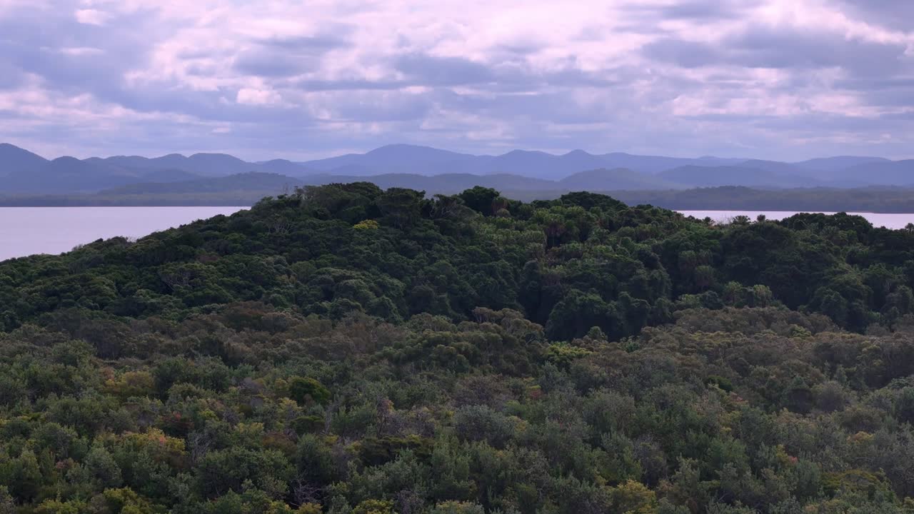 un lago rodeado de árboles y montañas bajo un cielo nublado con algunas nubes en la distancia con algunas nubes en el cielo